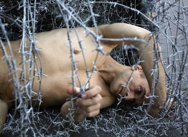 Artist Pyotr Pavlensky lies on the ground, wrapped in barbed wire roll, during a protest action in St. Petersburg
