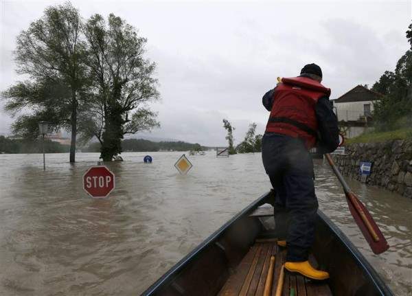 A member of the emergency services travels by boat along a flooded street in the Austrian village of Emmersdorf