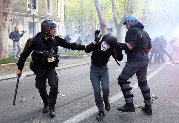 A demonstrator is detained by policemen during a protest in downtown Rome