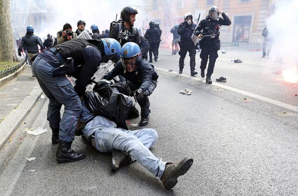 A demonstrator is detained by policemen during a protest in downtown Rome