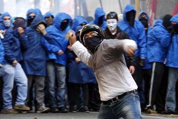 A demonstrator throws a stone at policemen during a protest in downtown Rome