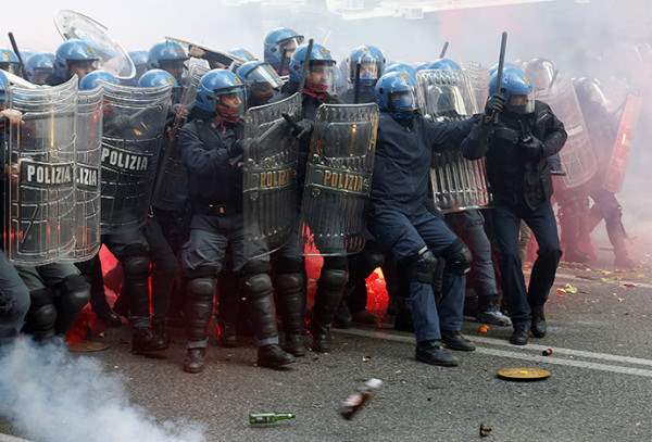 Policemen take shelter from bottles and flares thrown by demonstrators during a protest in downtown