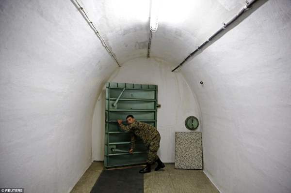 Солдат открывает металлическую дверь в бункере
