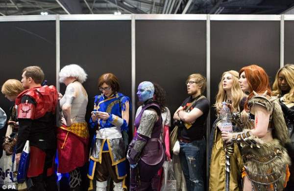 Комические поклонники, одетые в ослепительные  костюмы в очереди на Лондонский Super Comic Con.