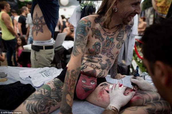 Израильский тату-мастер наносит рисунок на ногу любителю боди-арта.